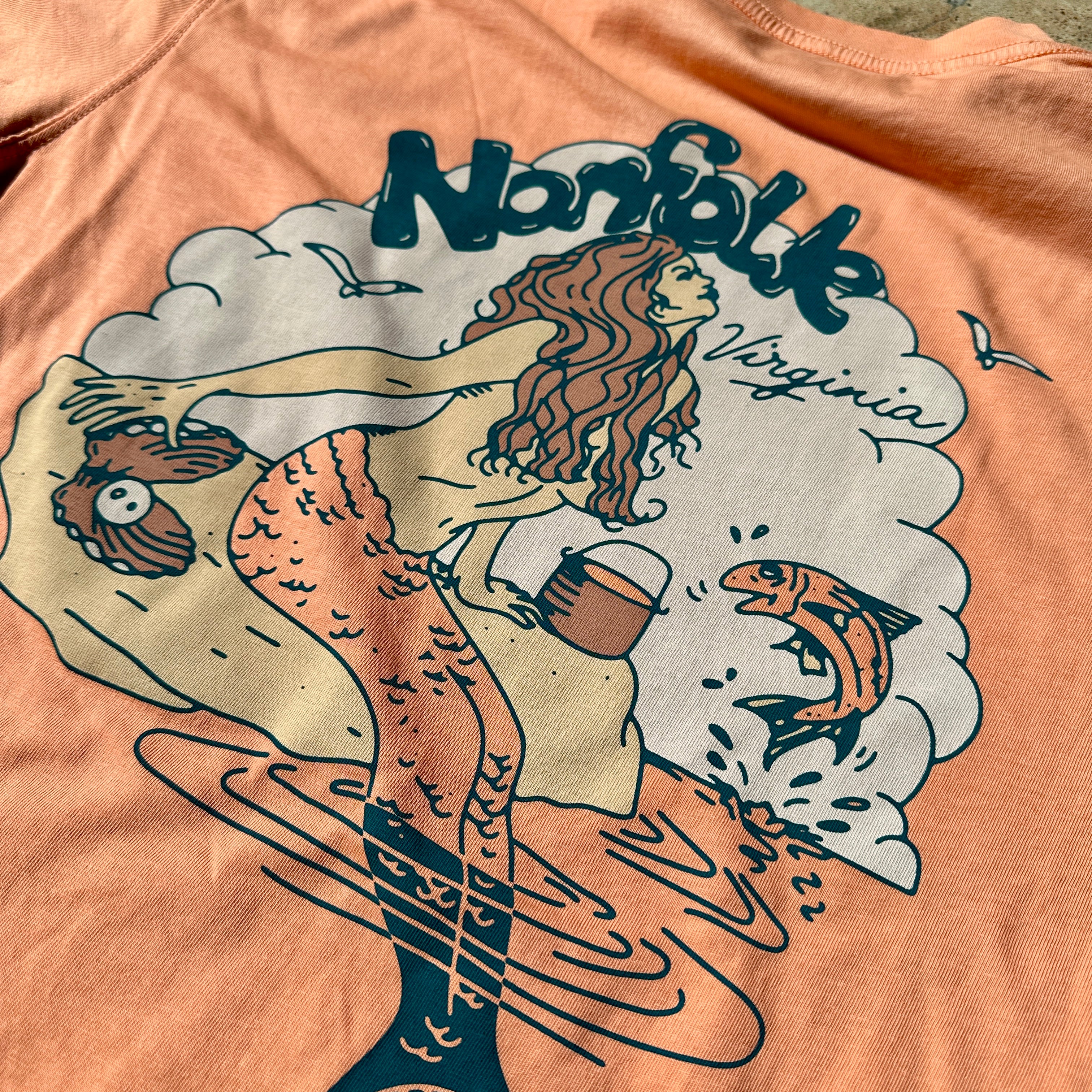 Closeup of an orange t-shirt printed with a retro-style mermaid and "Norfolk, Virginia"