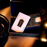 Card in a display case on a reflective surface with blurred lights in the background