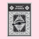 Card printed with a black and white design and a spinning arrow mounted in the center.