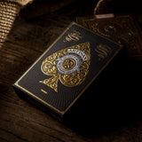 Playing cards with gold and black design on a wooden surface