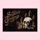 Black postcard with an ivory & gold illustration of a skull and candles, and the legend "Season's Greetings"