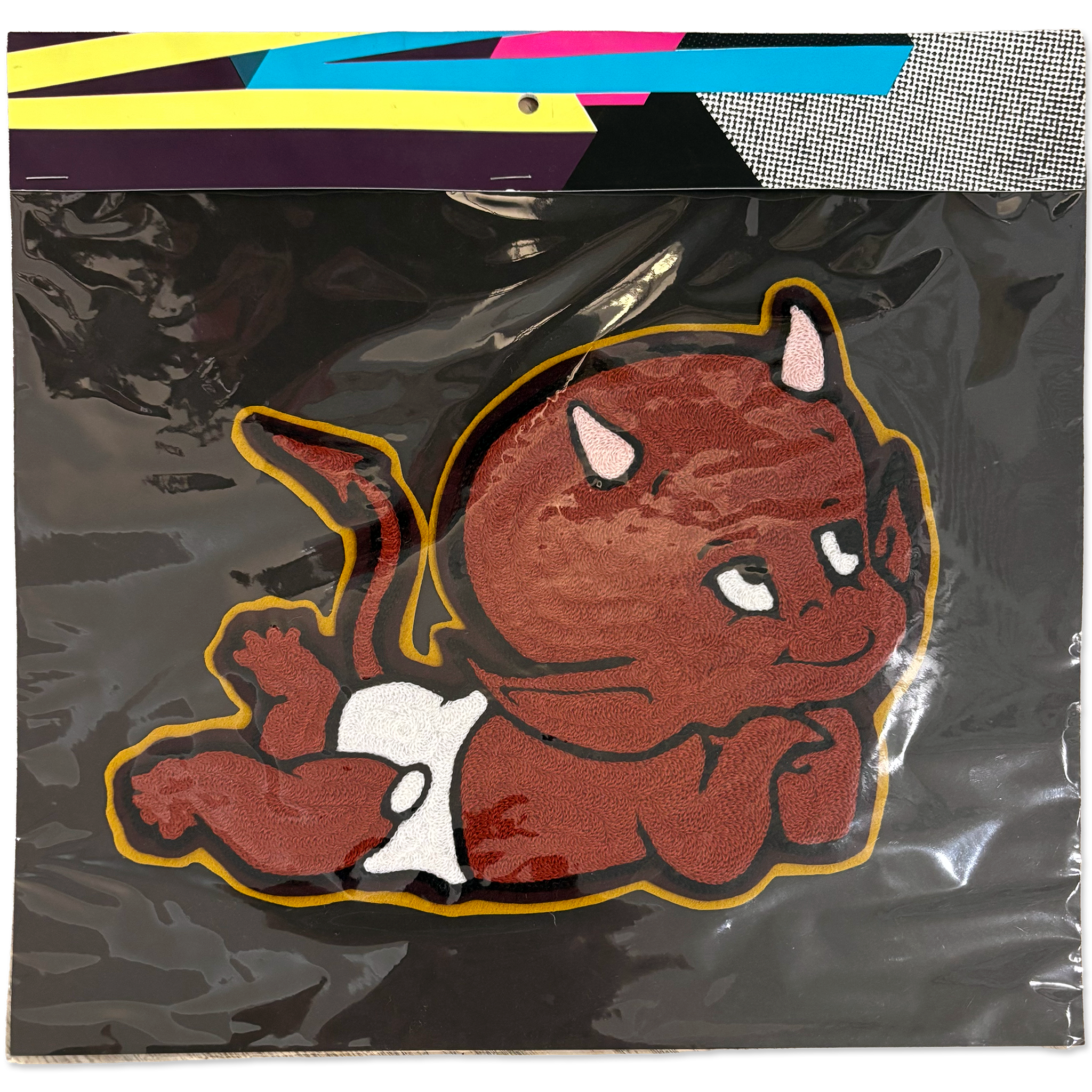 A packaged handmade chainstitch patch featuring a cartoon devil baby on a black backing, with a colorful header card visible at the top.