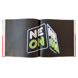 double-page spread of a nighttime photograph of a neon sign that says NEON