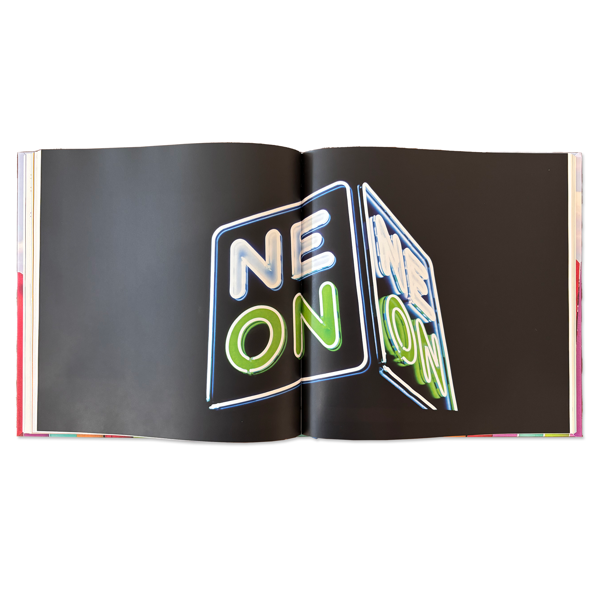 double-page spread of a nighttime photograph of a neon sign that says NEON