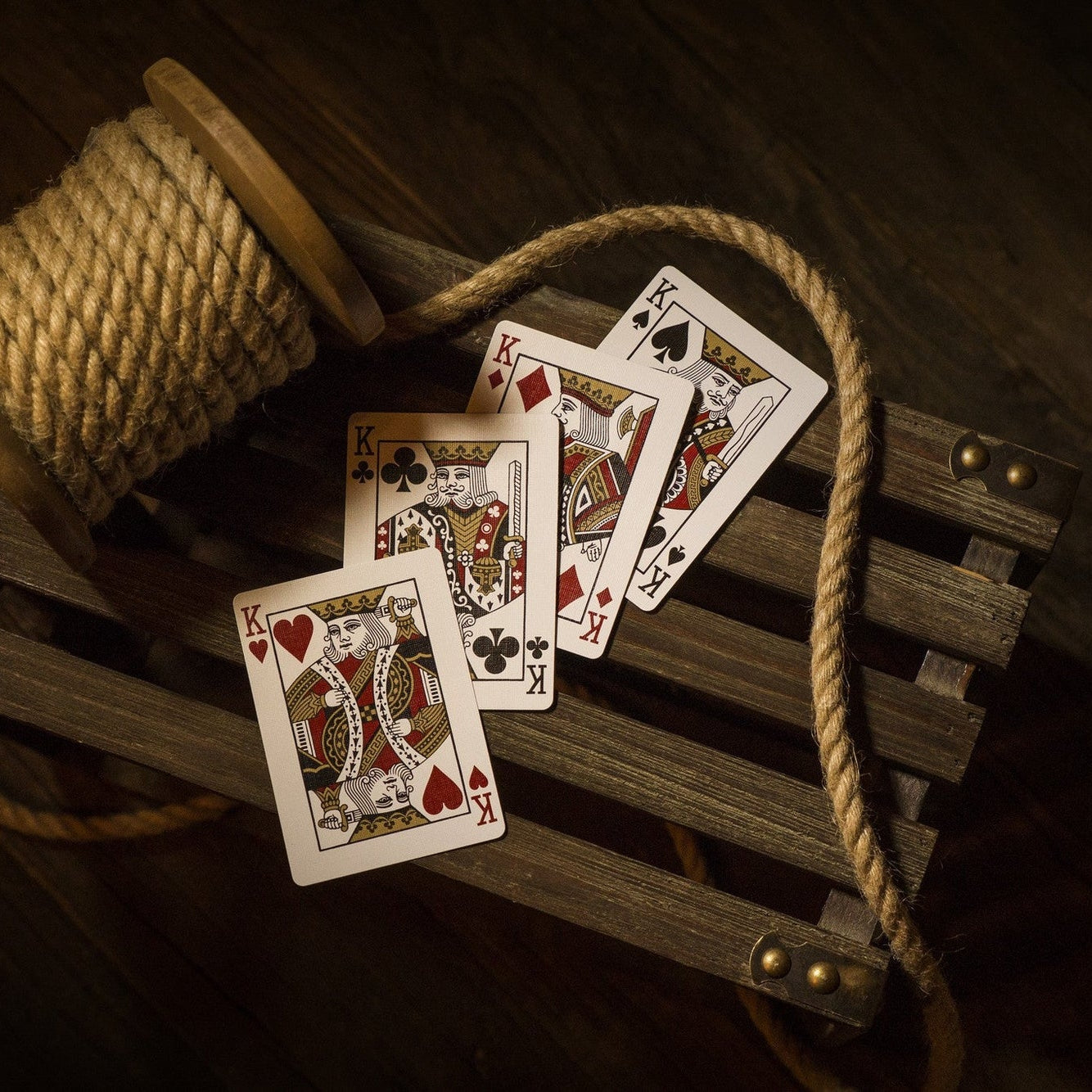 Playing cards on a wooden surface with rope and spool of thread.
