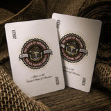 Two playing cards with a logo and text on a textured surface