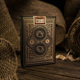 Vintage-style playing card box with intricate designs on a wooden surface.