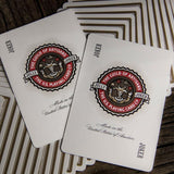 Two playing cards with a visible brand logo on a wooden surface