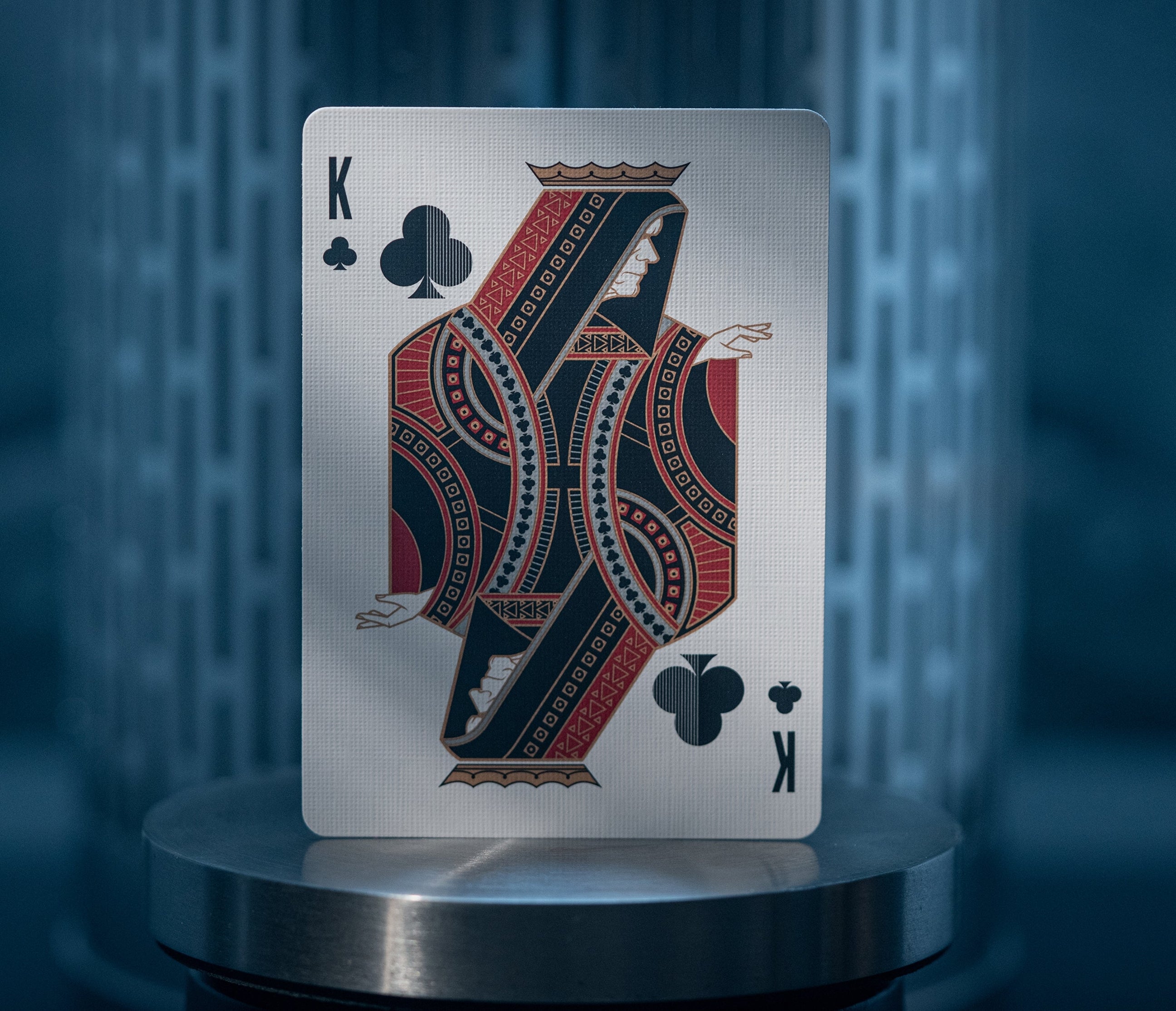 King of Clubs playing card on a reflective surface with a blurred background