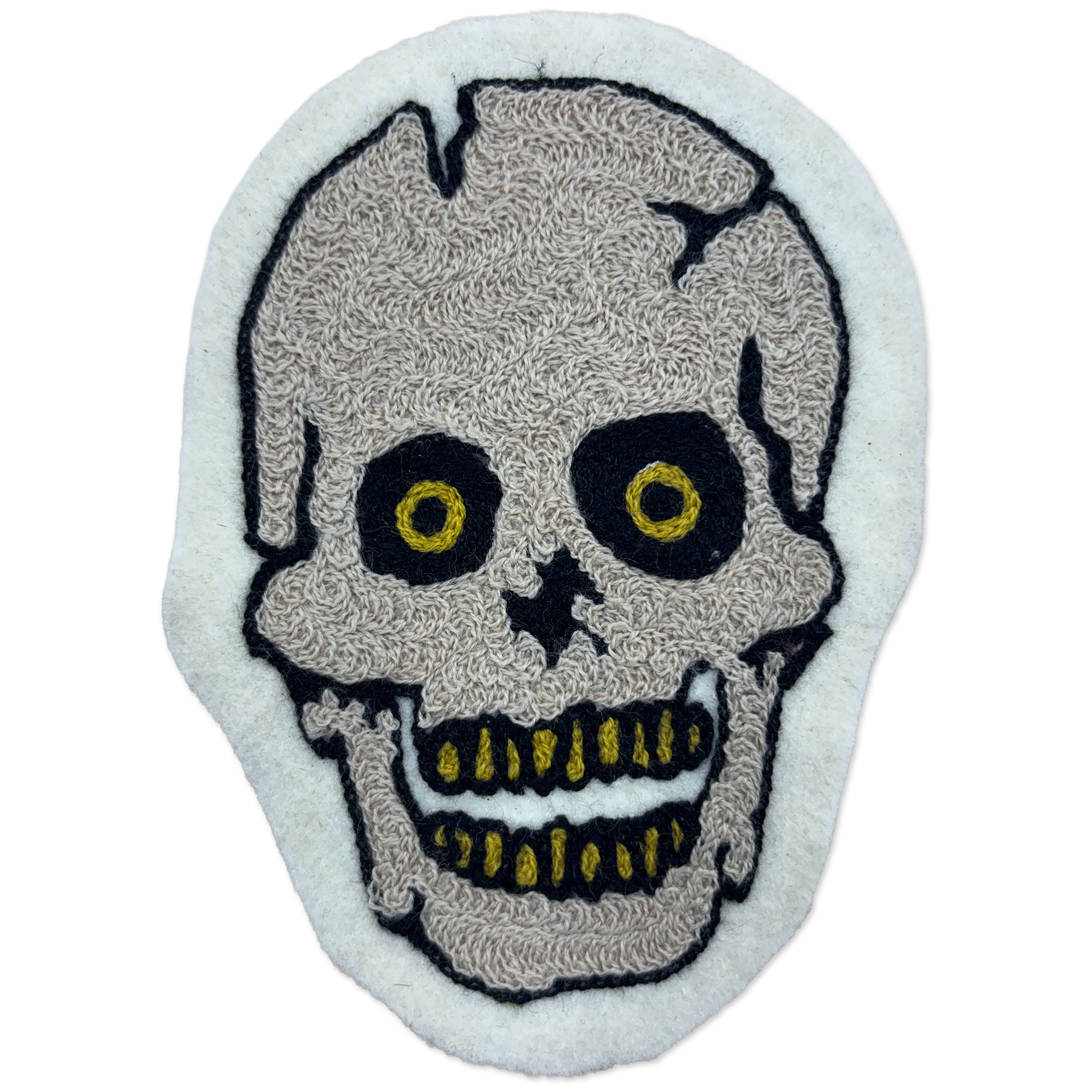 A skull-shaped embroidered patch with a textured beige skull design, black outlines, and yellow details on a white felt background.
