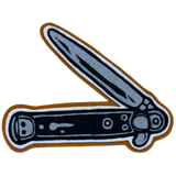 An embroidered patch of a folding pocket knife shown open, featuring a textured gray blade and handle with black details, a brown outer border, and a white inner outline, isolated on a white background.