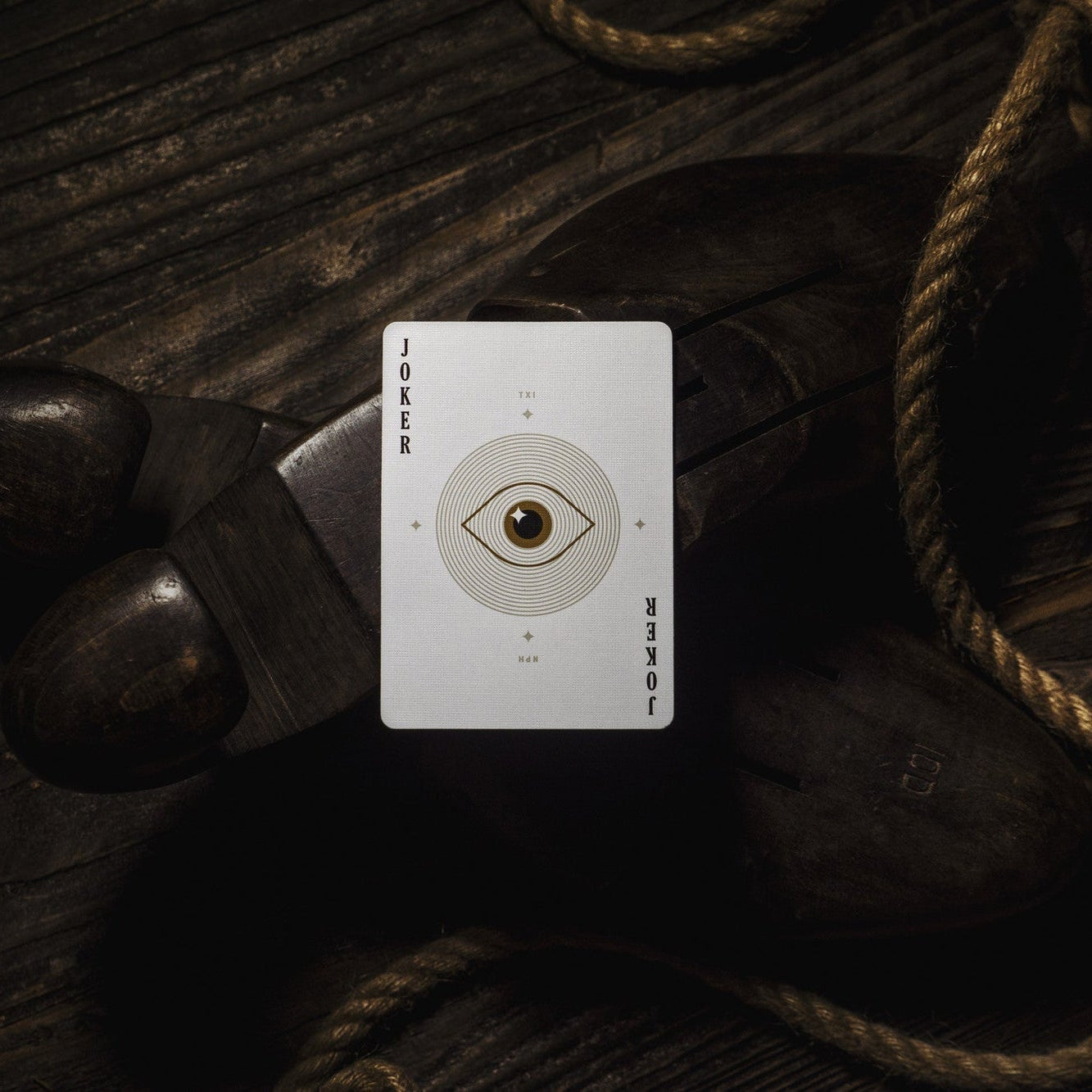 Card with an eye design on a dark wooden surface with ropes
