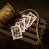 Playing cards on a wooden surface with rope and spool of thread.