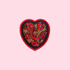 Black, red, and gold heart-shaped patch with cobra and flowers design
