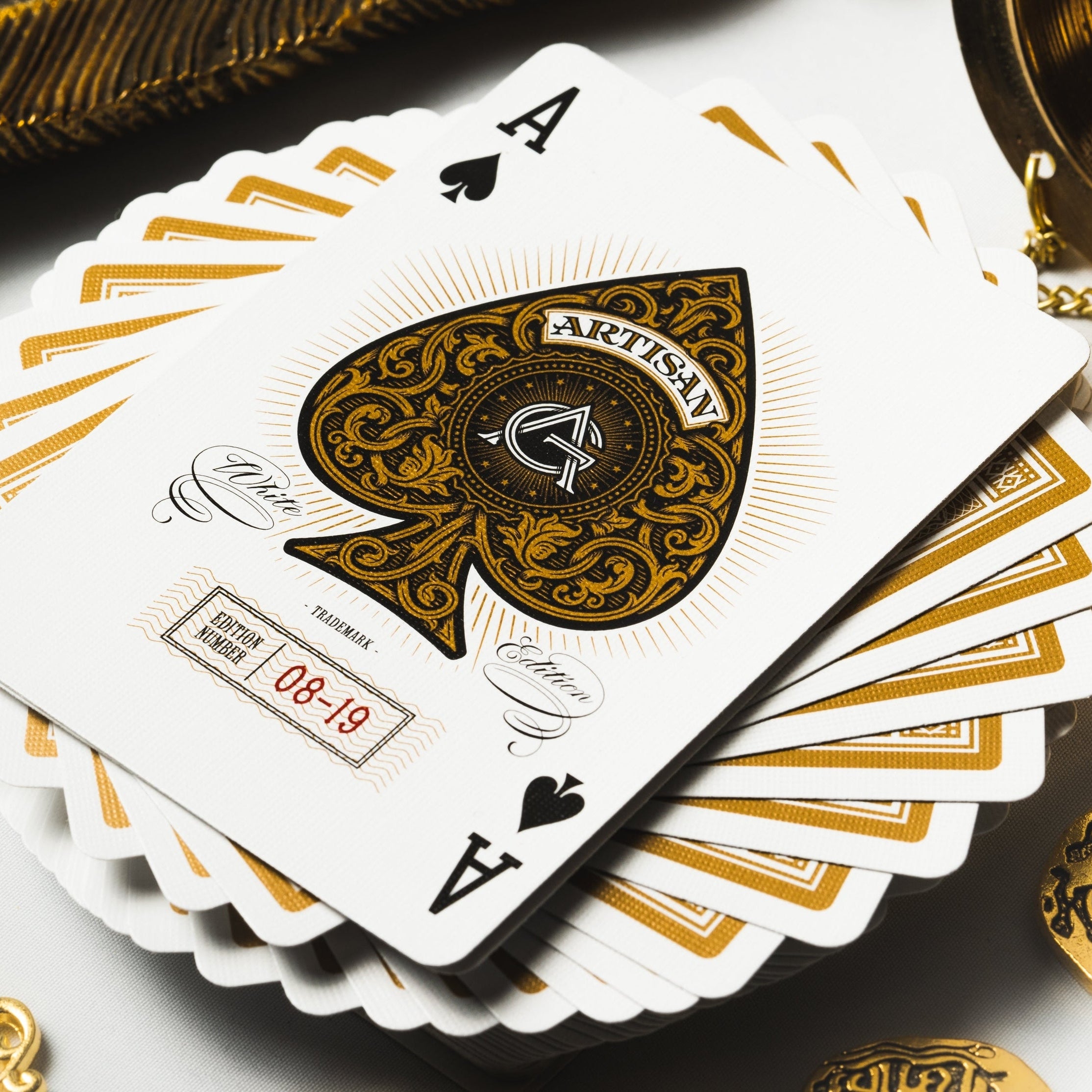 Playing cards with gold and black design on a white surface with coins.